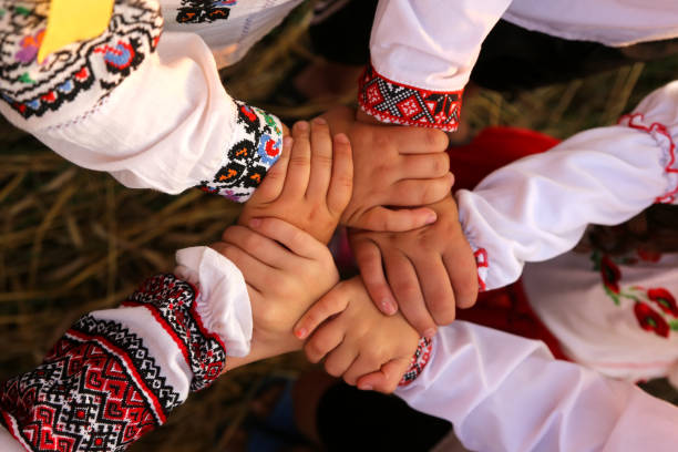 Children in embroidered shirts hold hands together in a symbol of unity.